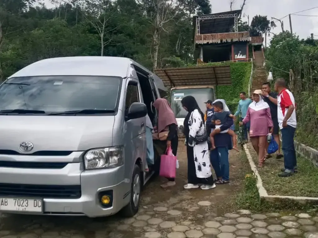 Penumpang berdiri di samping unit HiAce sebelum keberangkatan